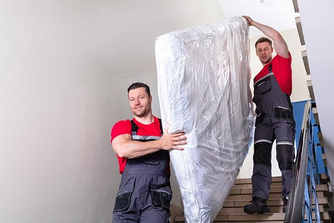 workers maneuvering a box spring through a narrow hallway in North Richland Hills TX