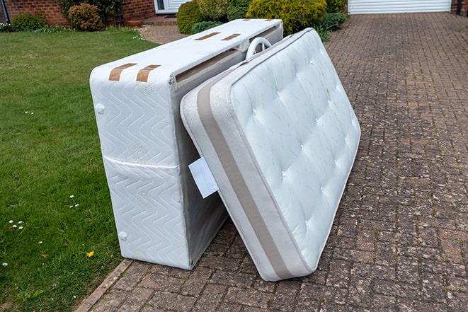 old mattress being hauled away by two people